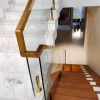 Glass staircase railing with polished gold handrail