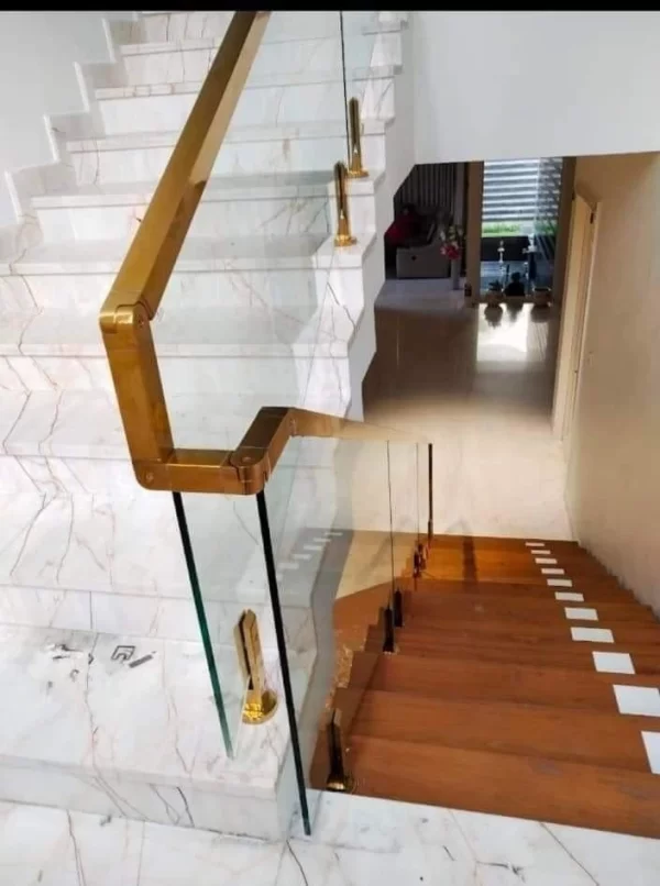 Glass staircase railing with polished gold handrail